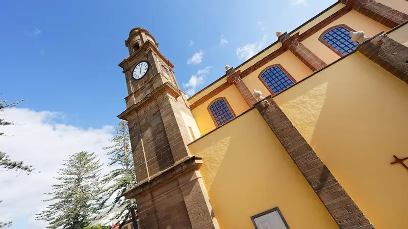 Façade d'un bâtiment jaune avec une tour horlogée en pierre.