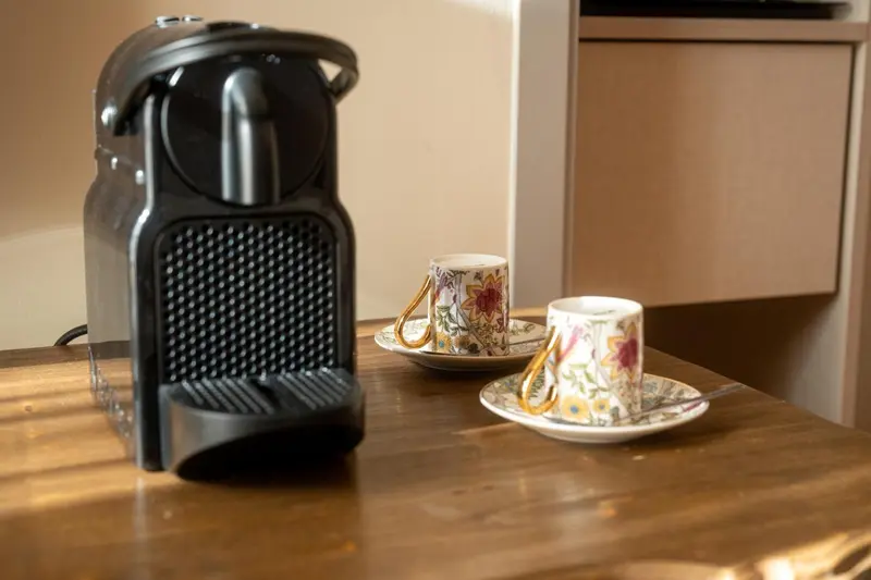 Une machine à café et deux tasses sur une surface en bois.