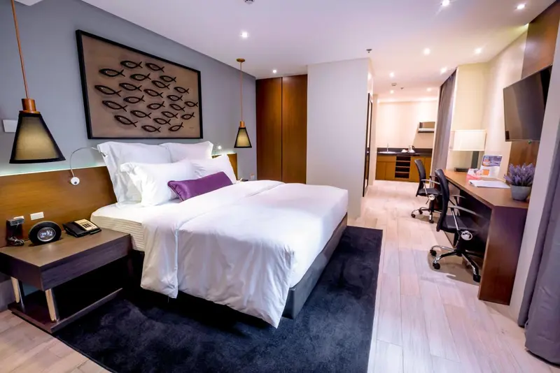 Chambre moderne avec un grand lit et un espace bureau.