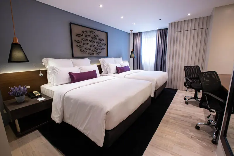 Une chambre moderne avec deux lits simples et un espace de travail.
