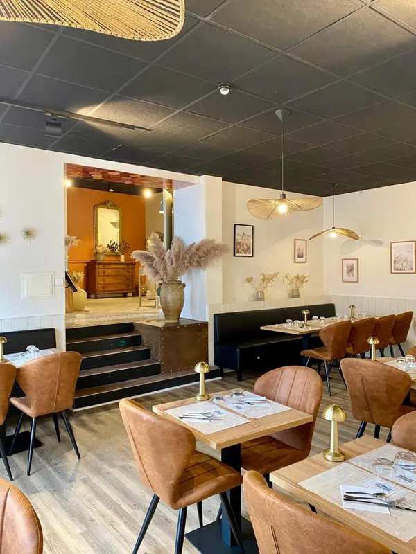 Une salle de restaurant avec des tables dressées et un éclairage tamisé.
