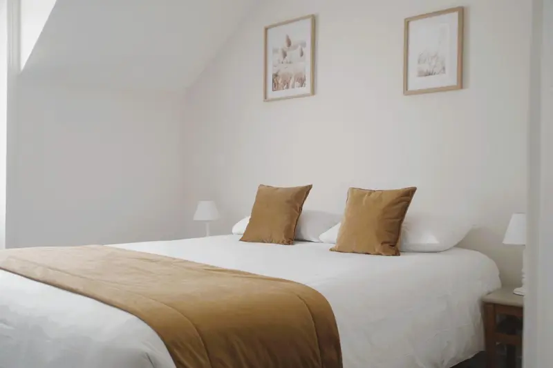 Une chambre lumineuse avec un grand lit recouvert d'une courtepointe et de coussins.
