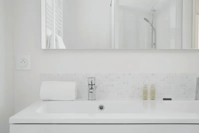 Un lavabo blanc avec un robinet chromé dans une salle de bain lumineuse.
