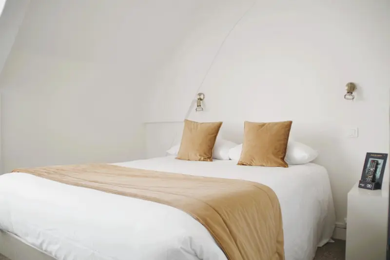 Une chambre lumineuse avec un grand lit recouvert d'une courtepointe.