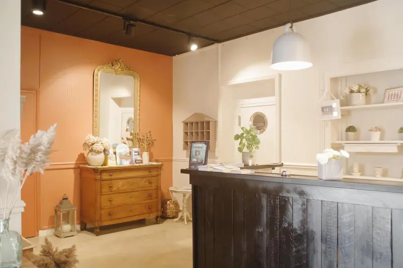 Un comptoir d'accueil décoré avec un miroir ancien et des plantes.