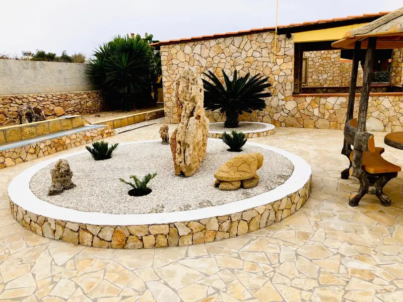 Un jardin zen avec des sculptures de pierre et des plantes.