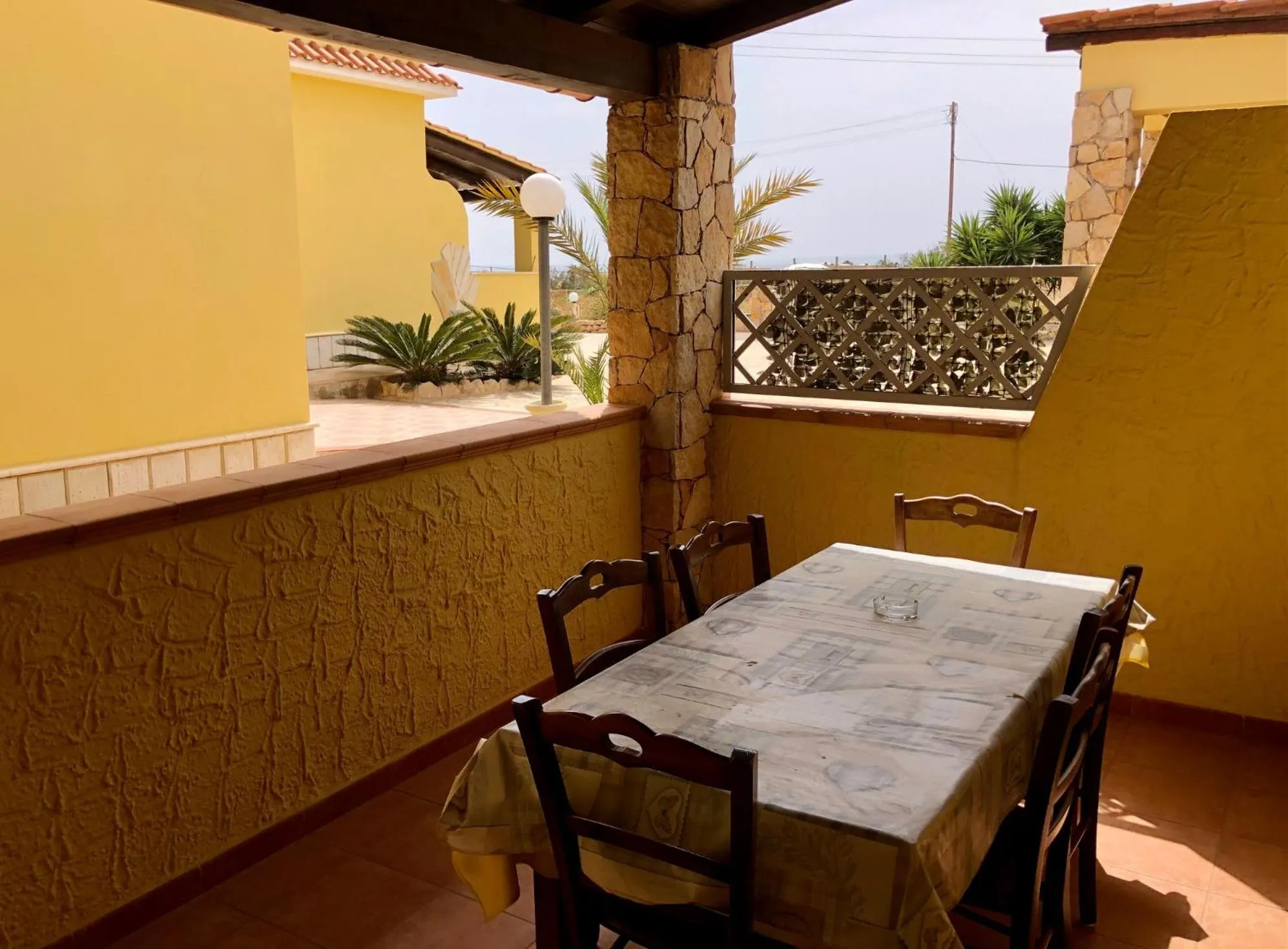 Table et chaises sur une terrasse ensoleillée avec vue sur la mer.