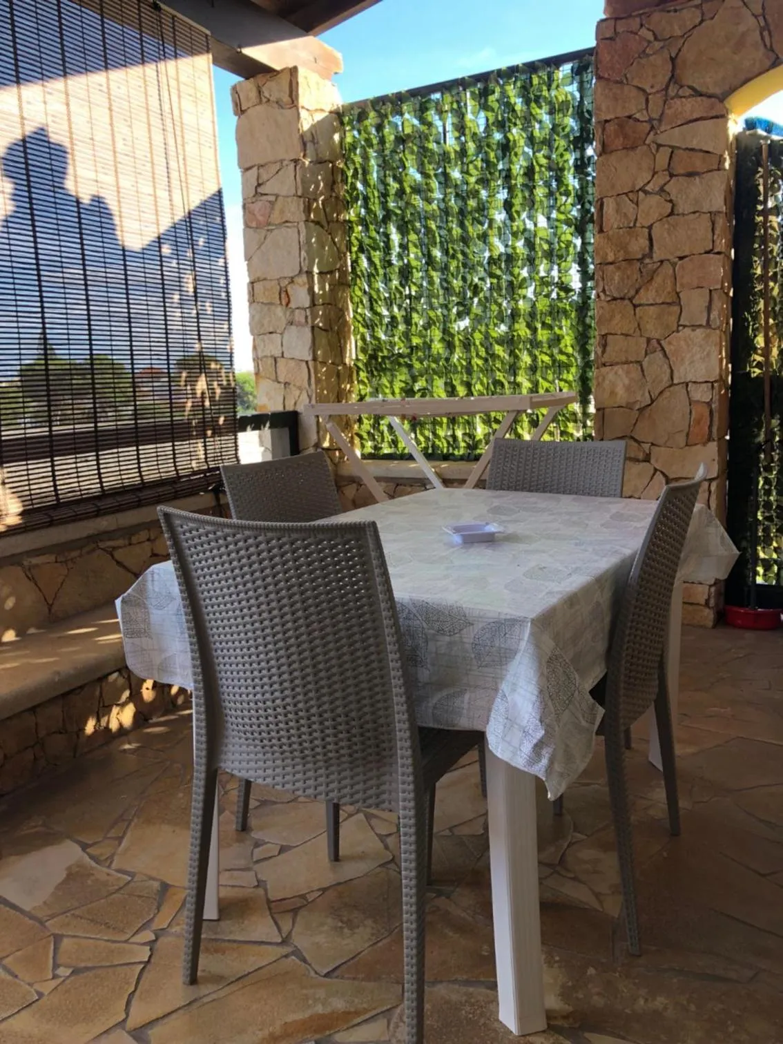 Une table à manger est mise en scène sur une terrasse ombragée.