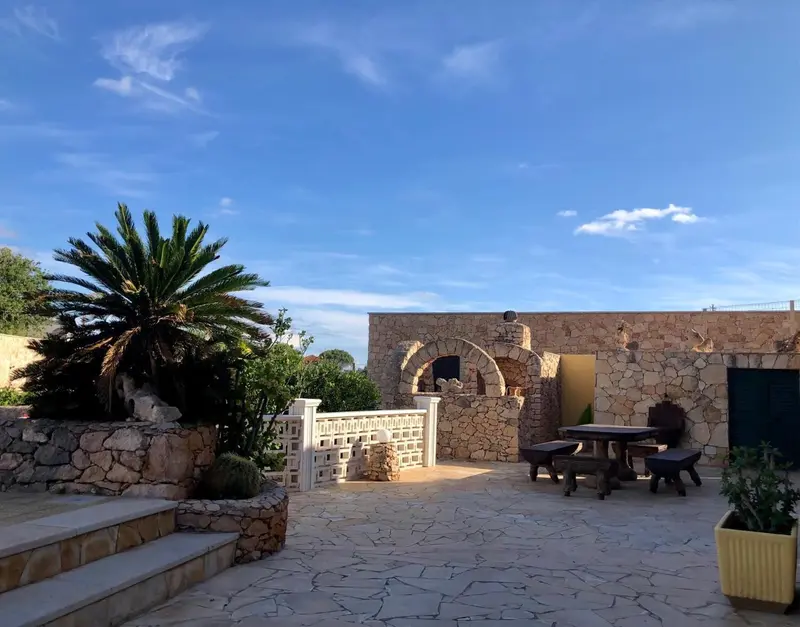 Terrasse pavée avec mobilier de jardin devant un bâtiment en pierre.