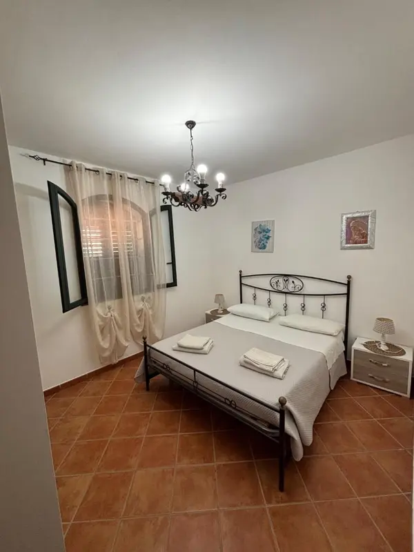 Une chambre lumineuse avec un lit double et des rideaux décoratifs.