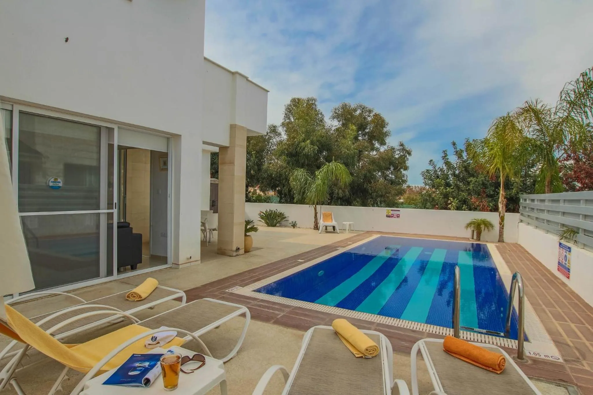 Terrasse avec transats et piscine rectangulaire.