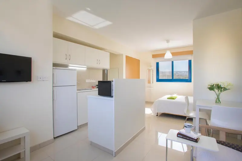 Une cuisine ouverte sur un espace de vie avec un lit et une table.