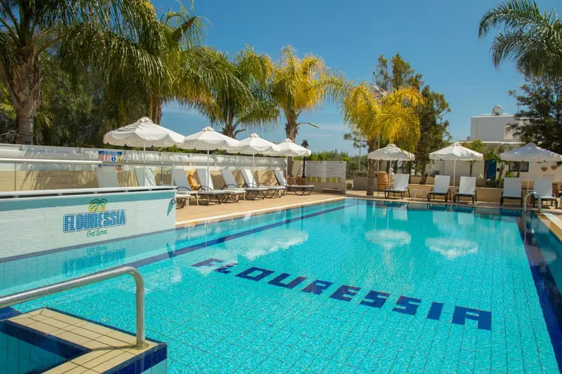Piscine rectangulaire bleue avec transats blancs et parasols.