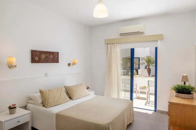 Une chambre lumineuse avec un lit et un accès à une terrasse.