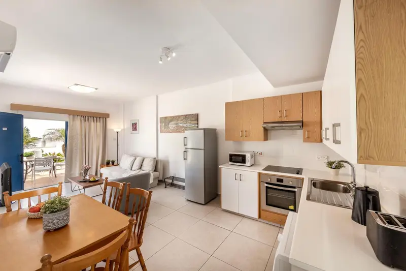 Une cuisine moderne s'ouvre sur un espace de vie lumineux avec canapé et table à manger.