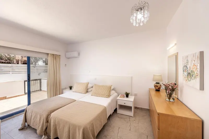 Chambre lumineuse avec deux lits simples et une décoration sobre.