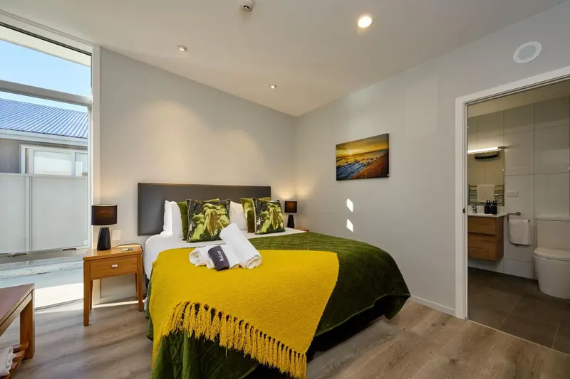 Une chambre lumineuse avec un grand lit recouvert d'une couverture jaune et verte.