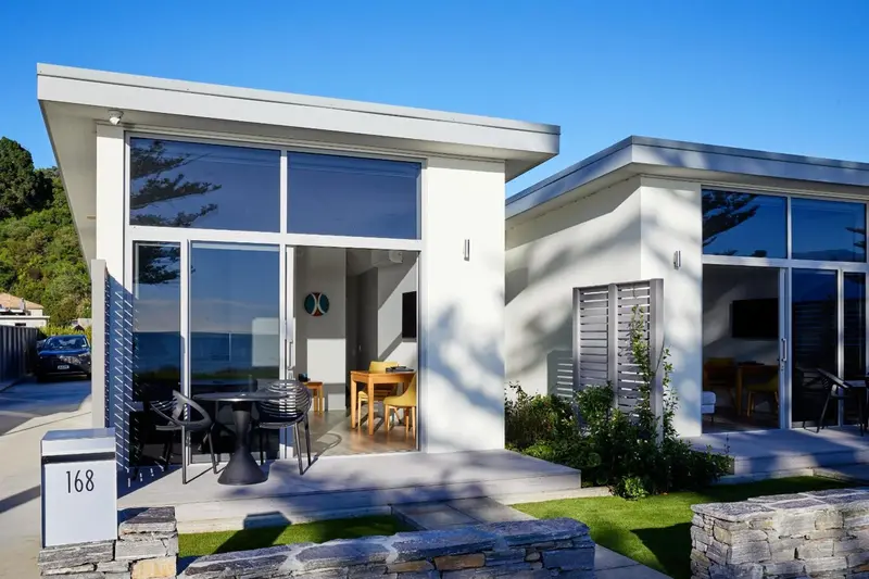 Façade d'un bâtiment moderne avec une terrasse et du mobilier de jardin.