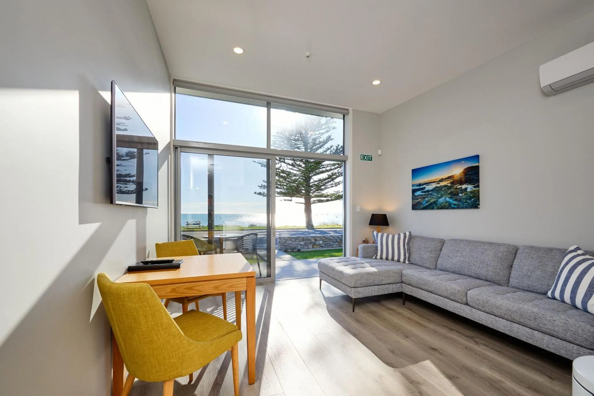 Espace de vie lumineux avec canapé, table et vue sur la mer.