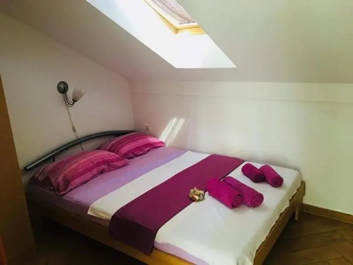 Une chambre mansardée avec un lit recouvert d'une couverture violette.
