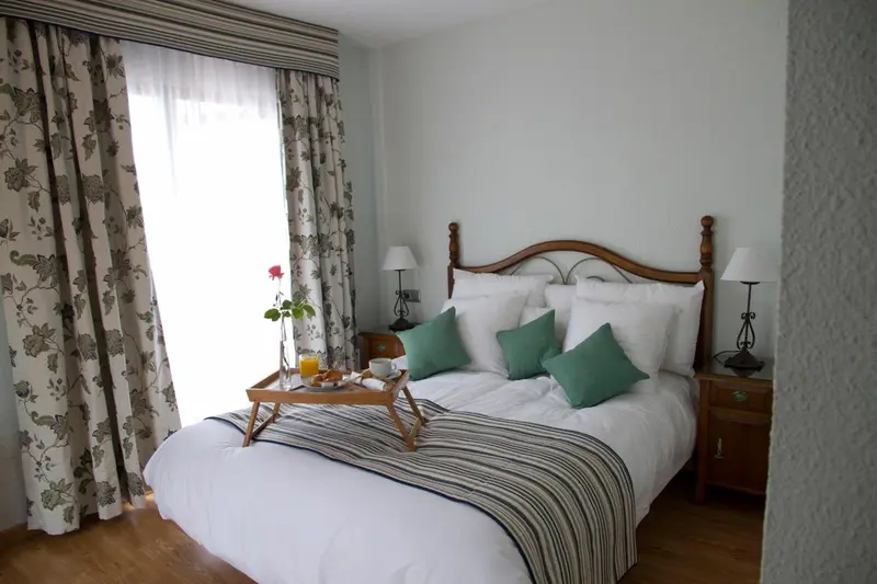 Une chambre lumineuse avec un grand lit et un plateau de petit-déjeuner.