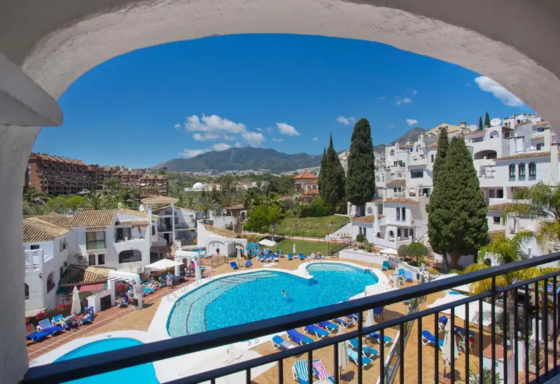 Vue sur une piscine et un paysage montagneux depuis un balcon.
