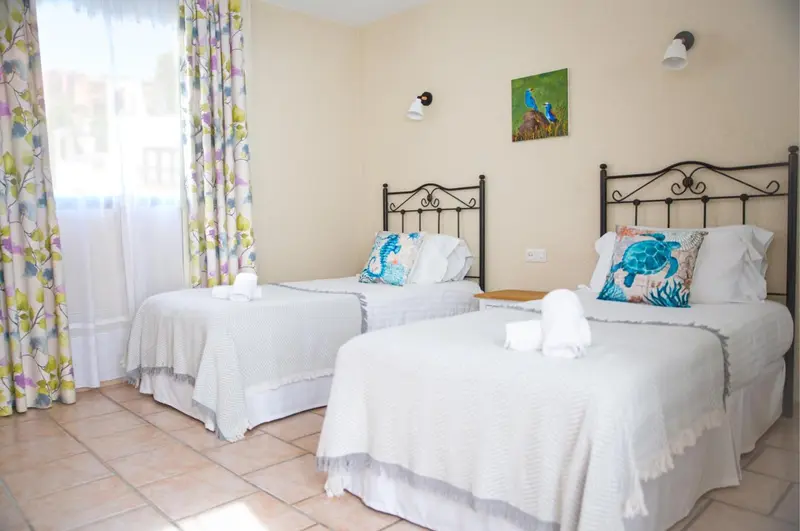 Deux lits simples dans une chambre lumineuse avec décoration florale.