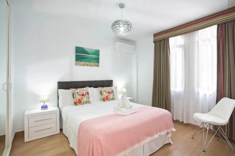Une chambre lumineuse avec un grand lit recouvert d'une couverture florale.