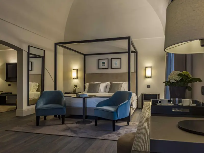 Une chambre lumineuse avec un lit à baldaquin et deux fauteuils.