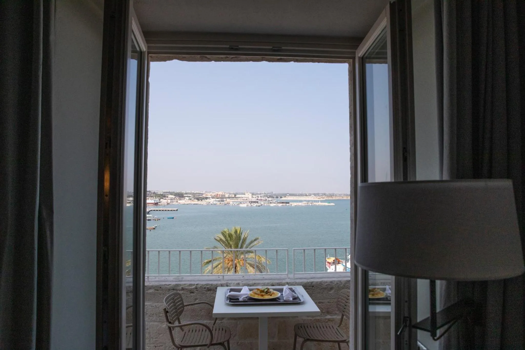 Vue sur la mer depuis une chambre avec une table et des chaises sur un balcon.