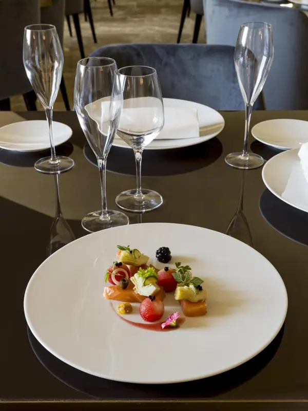 Une table est dressée avec des assiettes décorées et des verres à vin.