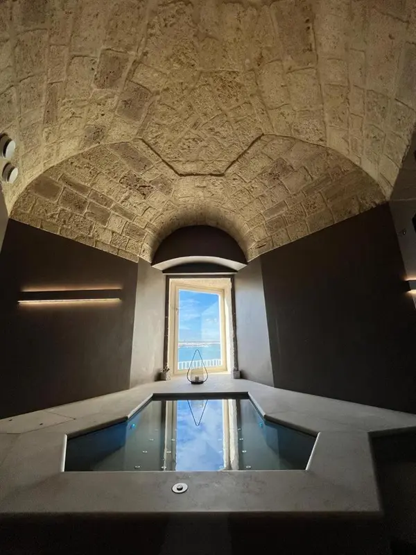 Une piscine intérieure avec un mur en pierre et une fenêtre ouverte sur l'extérieur.
