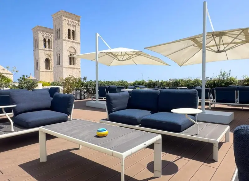 Terrasse aménagée avec des canapés et des tables basses, vue sur un édifice historique.