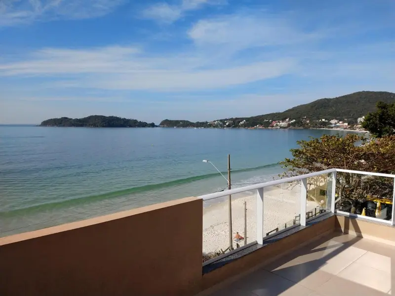 Vue sur une plage et la mer depuis une terrasse ensoleillée.