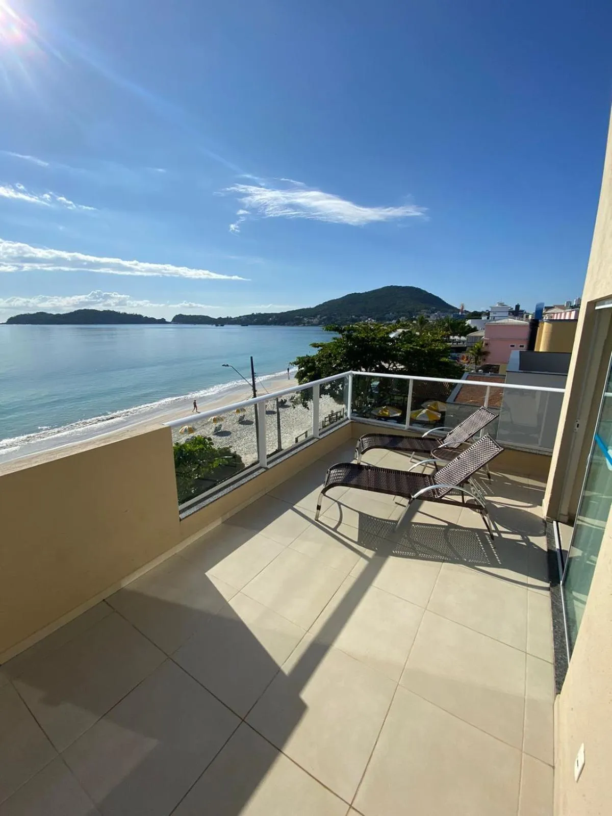 Terrasse ensoleillée avec mobilier de jardin et vue sur la mer.