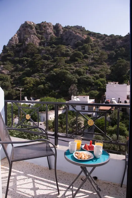 Une table ronde avec un petit-déjeuner est posée sur une terrasse ensoleillée.