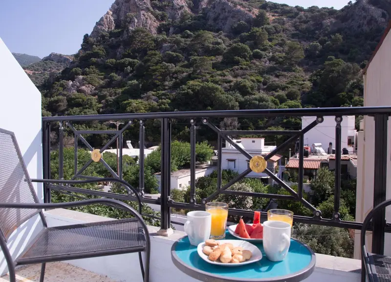 Une table basse turquoise accueillant un petit déjeuner sur un balcon avec vue sur un paysage montagneux.