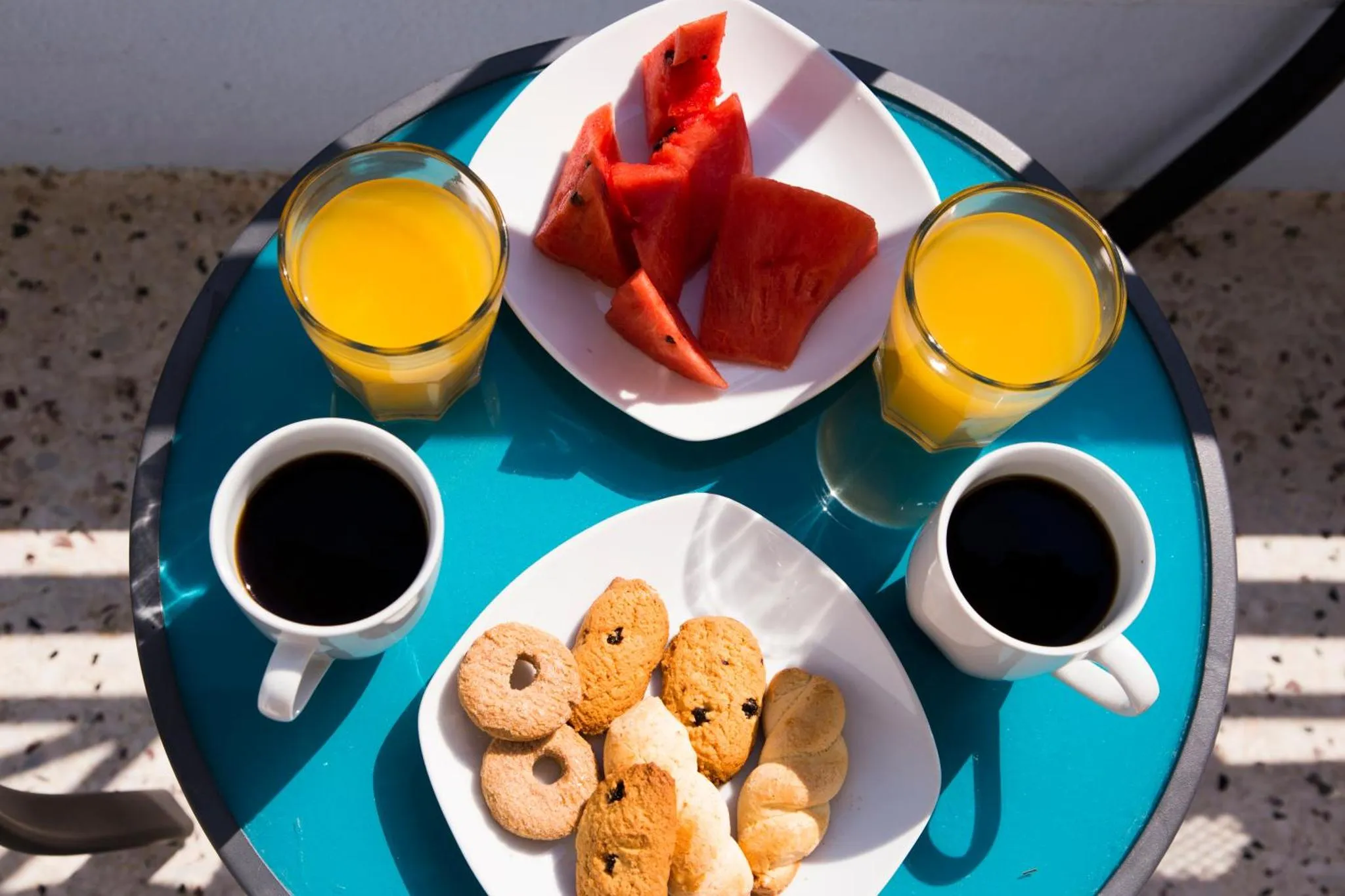 Une table ronde turquoise présente des boissons et des pâtisseries.