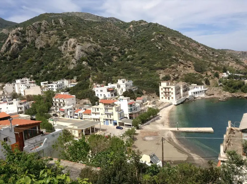 Vue aérienne d'un village côtier avec des bâtiments blancs et une petite plage.