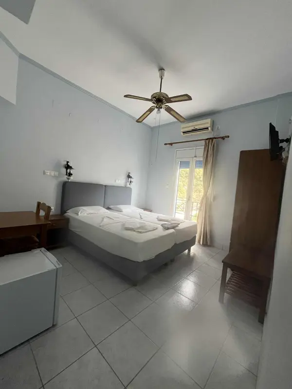 Une chambre lumineuse avec un lit double et un ventilateur au plafond.