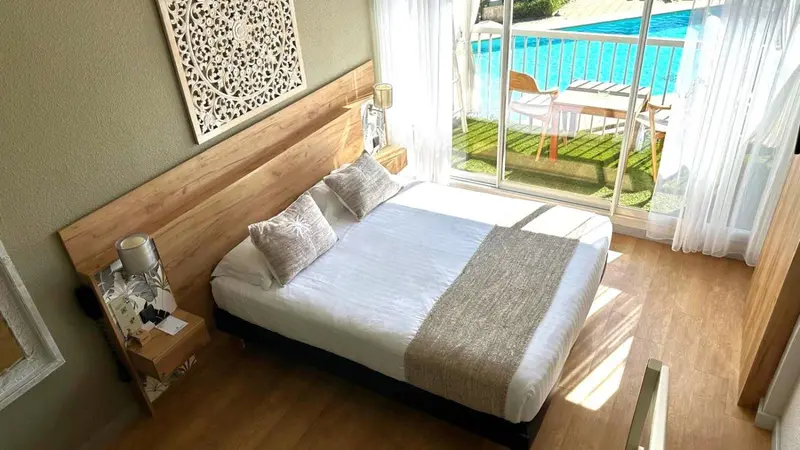 Une chambre lumineuse avec un lit double et un accès à une terrasse.