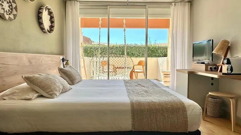 Une chambre lumineuse avec un lit fait et un accès à une terrasse.