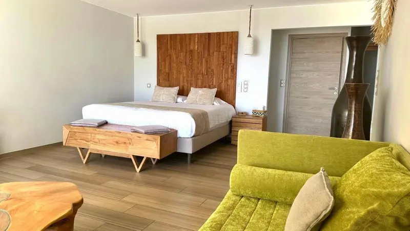 Une chambre lumineuse avec un grand lit et un coin salon vert.