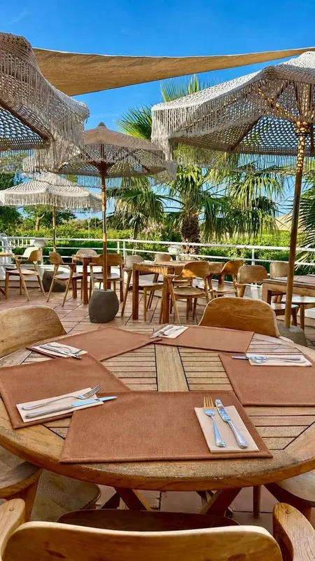 Tables dressées à l'ombre de parasols en terrasse.