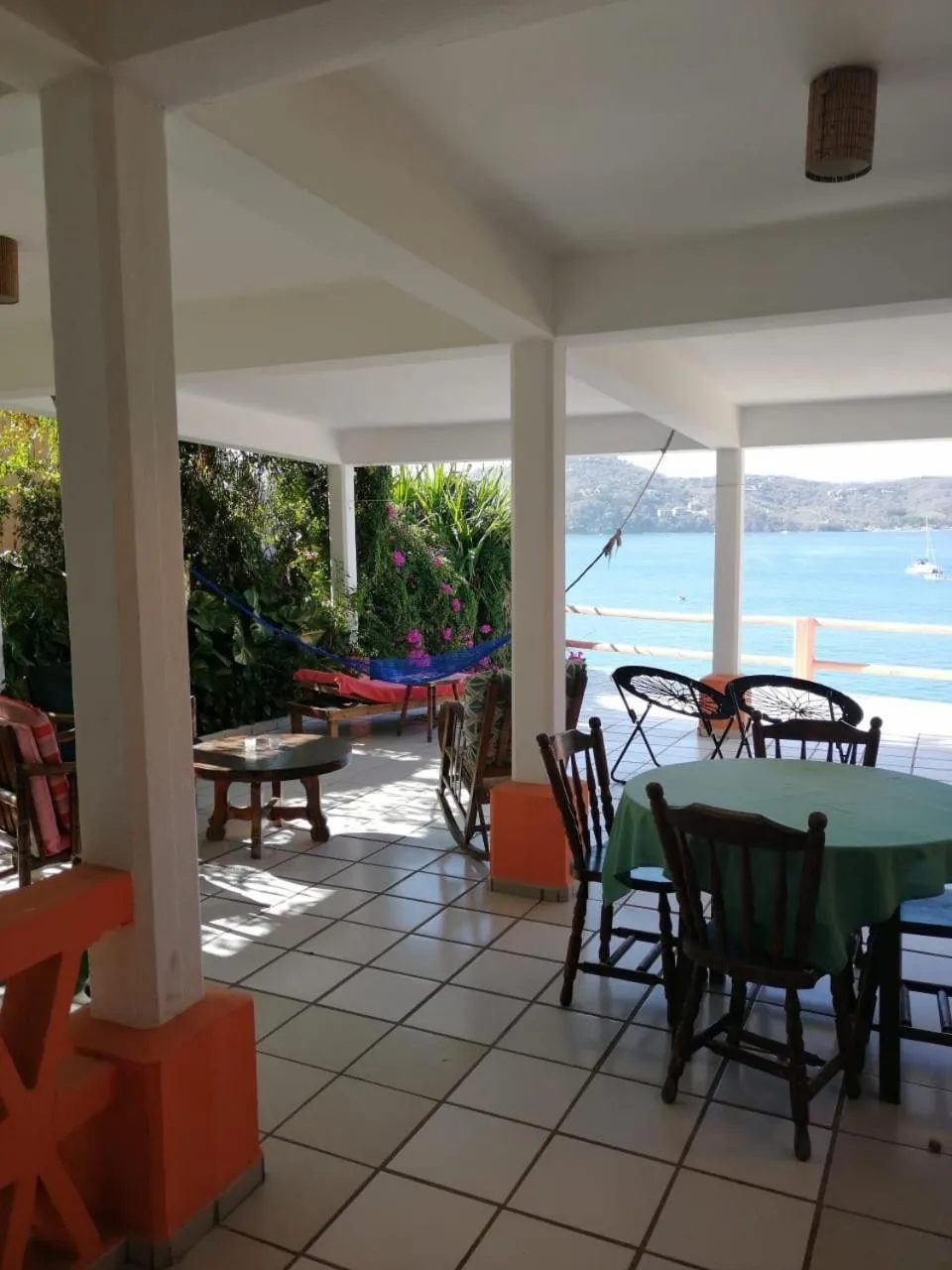 Terrasse ombragée avec tables et chaises donnant sur la mer.