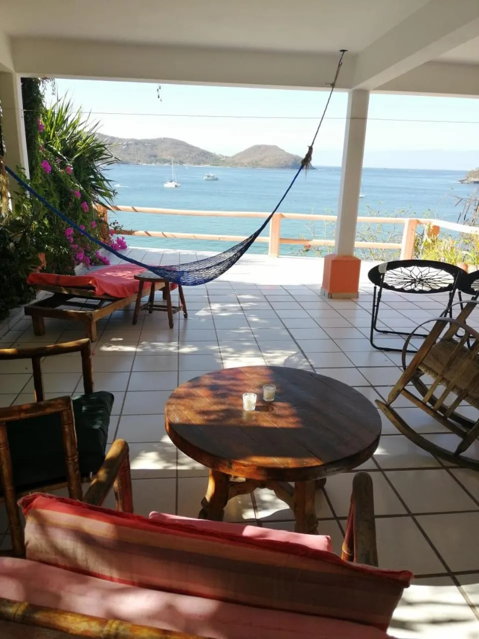 Terrasse ombragée avec mobilier de jardin et vue sur la mer.