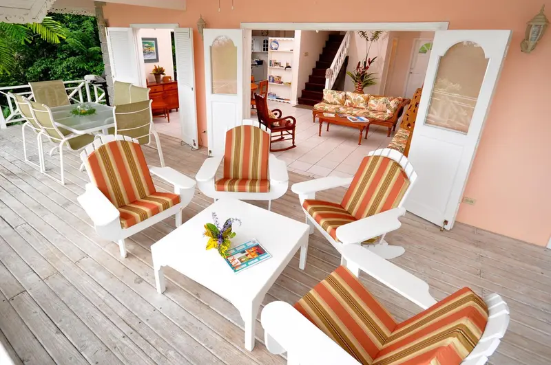 Terrasse aménagée avec mobilier blanc et coloré, donnant sur un espace intérieur lumineux.