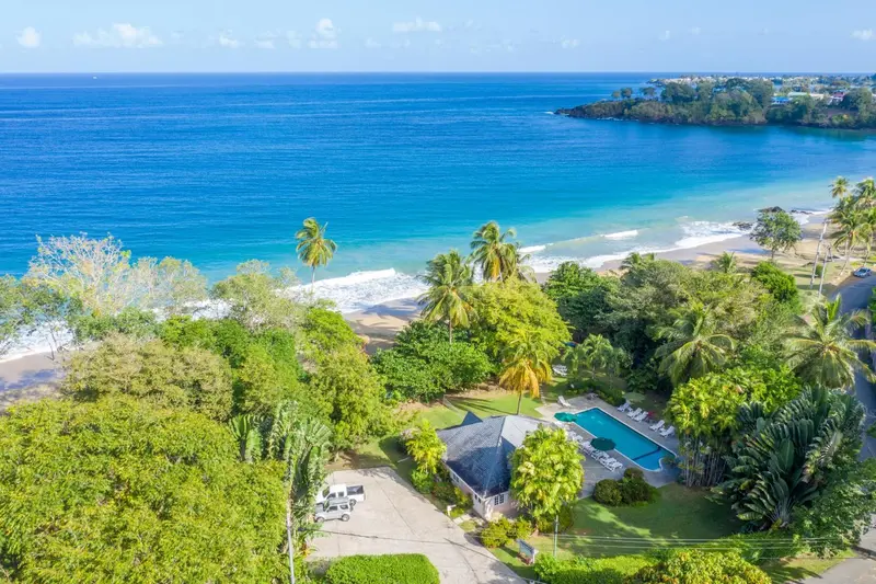Vue aérienne d'une plage bordée de végétation et d'une piscine d'hôtel.