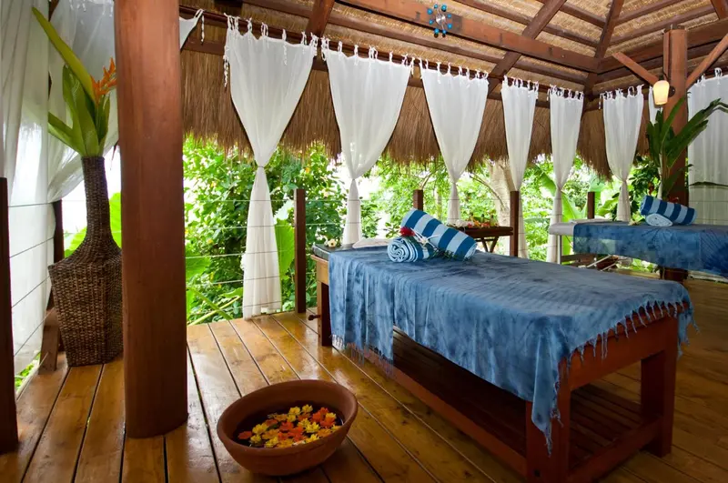 Deux tables de massage sont disposées sous une structure ajourée en bois et en tissu.