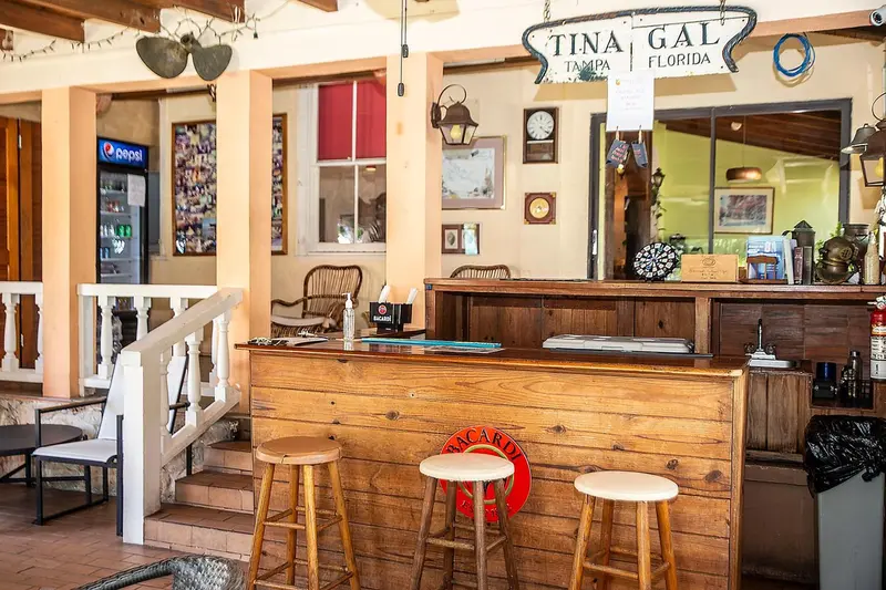 Un comptoir en bois clair avec des tabourets hauts dans un espace lumineux et décoré.